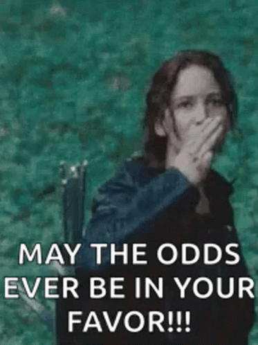 A woman covers her mouth while text says “MAY THE ODDS EVER BE IN YOUR FAVOR!!!”