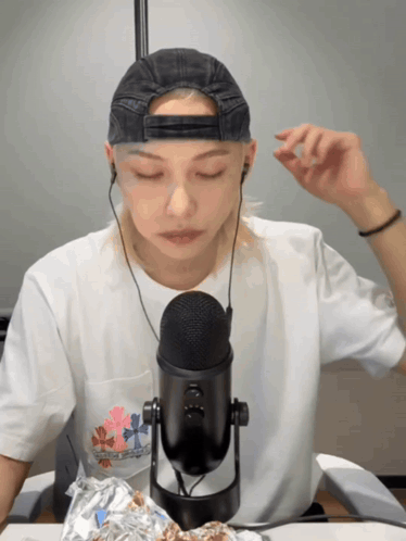 a person wearing a hat and ear buds looks at a microphone