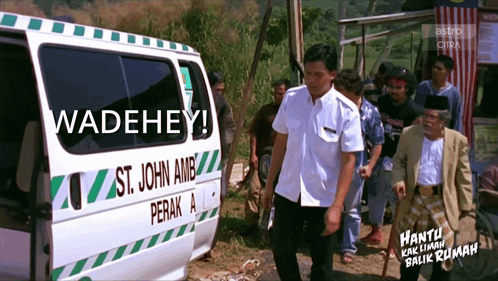 a man standing next to an ambulance that says st. john amb perak a
