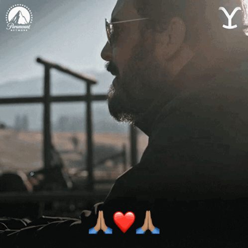a man with glasses and a beard is looking out a window with a paramount logo behind him
