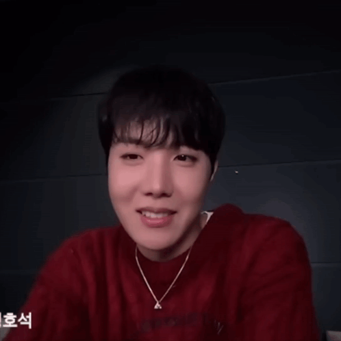 a man wearing a red sweater and a necklace with the letter a on it