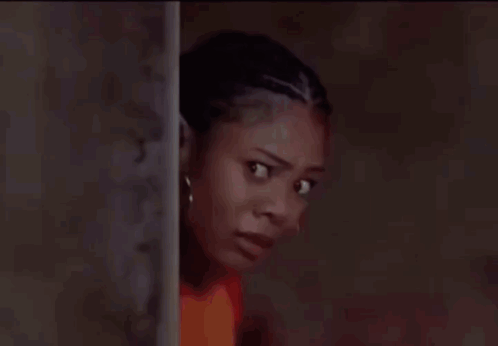 A woman looks sideways with a frightened, wary expression.