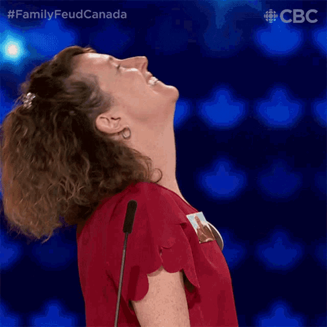 a woman in a red shirt is standing in front of a microphone and looking up ..