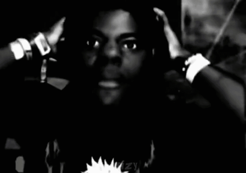A black-and-white shot of a person in headphones looking distressed with hands at their head.