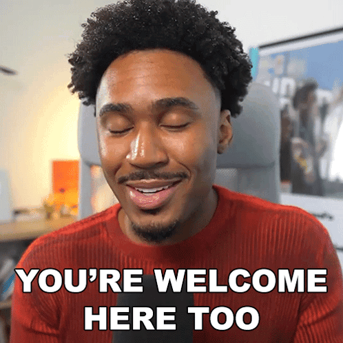 a man in a red sweater is smiling and saying you 're welcome here too