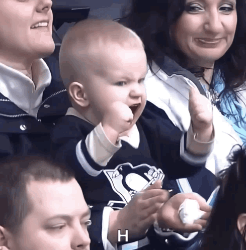 A child cheers in a Pittsburgh Penguins shirt among a crowd.