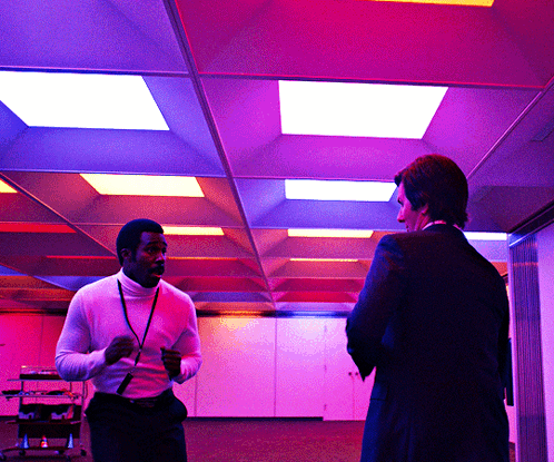 two men are standing in a room with purple lights