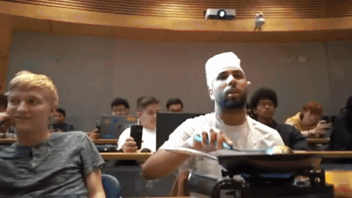 a man with a bandage on his face is sitting in a classroom with other students