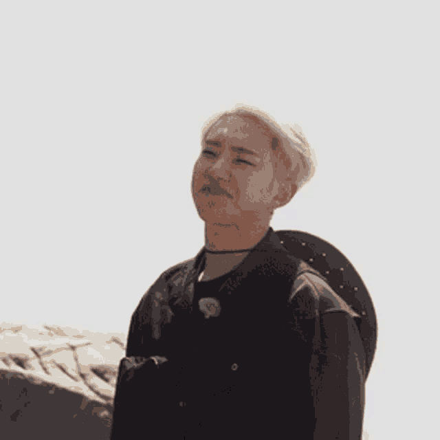 a young man with blonde hair is wearing a black jacket and choker