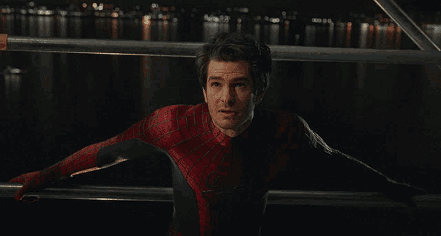 a man in a spiderman costume stands in front of a body of water at night