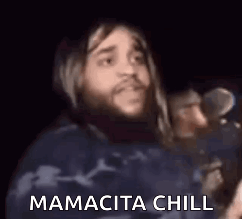 A bearded man holding a microphone says “МАМАСИТА CHILL.”