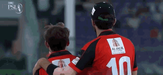 a man wearing a red and black jersey with the number 10 on it is hugging another man .