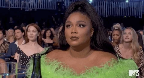 Lizzo gives an indifferent shrug on an awards-show stage.