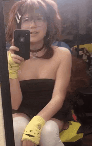a woman is taking a selfie in front of a mirror while wearing yellow gloves .