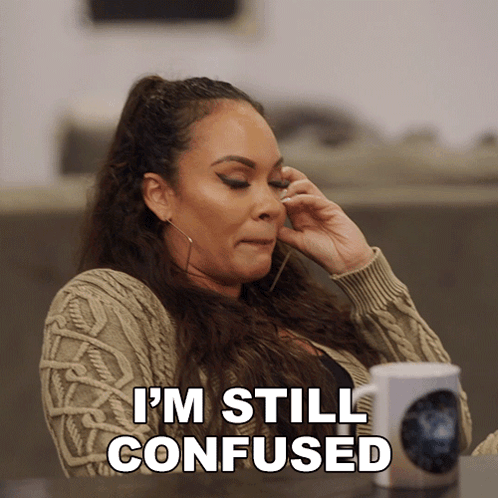 a woman sitting at a table talking on a cell phone with the words " i 'm still confused " next to her