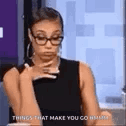 A woman wearing glasses gives a skeptical side-eye while holding a drink.