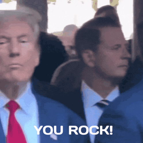 a man in a suit and tie is standing next to another man who says you rock