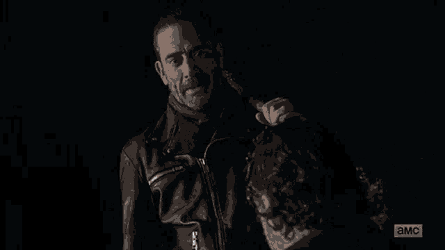 a man in a leather jacket is talking to another man in a dark room and the words `` not cool '' are visible .