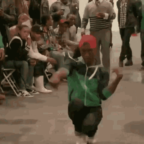 a man is dancing in front of a crowd of people .