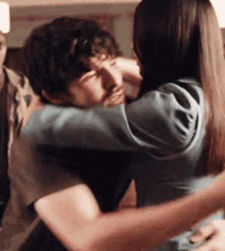 A couple embraces closely in a warm indoor scene.