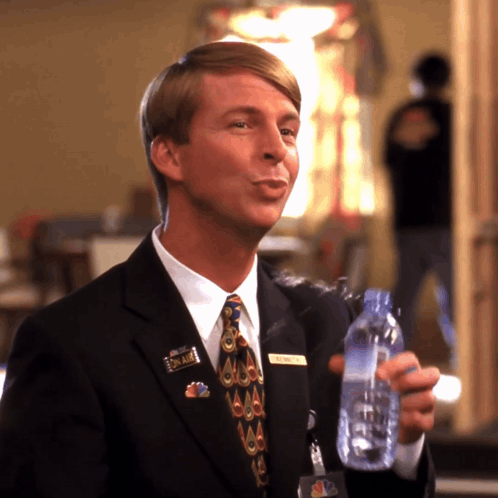 A man in a suit holds a drink and visibly shakes with nervous tension.