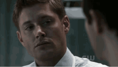 a man in a white shirt is looking at another man .