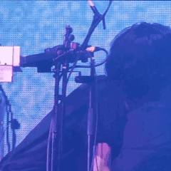 a man in a black shirt is dancing in front of a purple and blue screen .