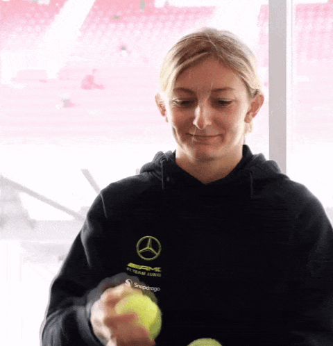 a woman wearing a black shirt that says amg on it is holding a tennis ball