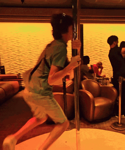 a man in a green shirt is holding a pole in a room