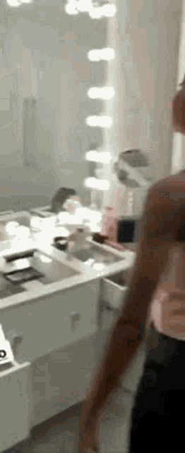 a man is standing in a bathroom in front of a vanity mirror .