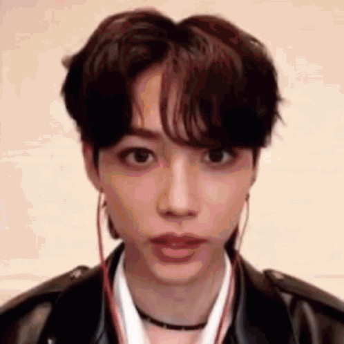a close up of a young man wearing a leather jacket and earphones .