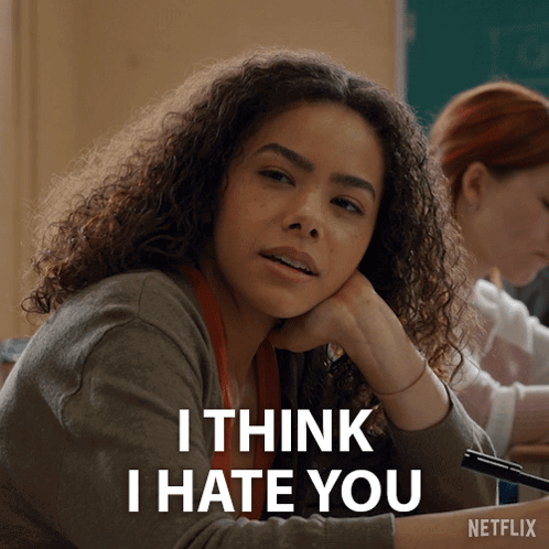 a girl with curly hair is sitting in a classroom with the words i think i hate you on the bottom