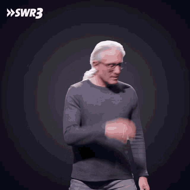 a man wearing glasses and a ponytail is dancing in front of a swr3 sign