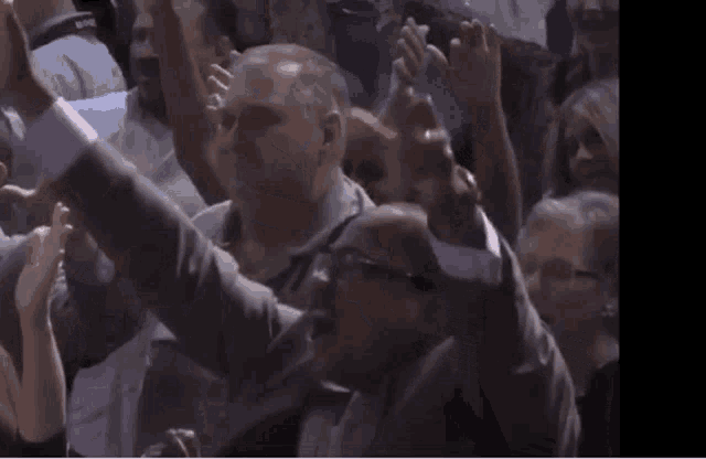 a group of people are sitting in a crowd with their arms in the air