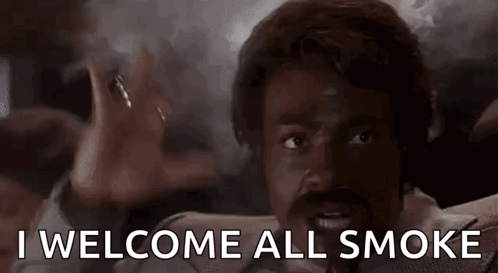a man with a beard and mustache is smoking a cigarette and says `` i welcome all smoke '' .