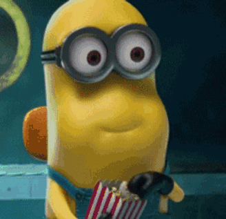 A Minion stares wide-eyed while holding a striped popcorn bucket.