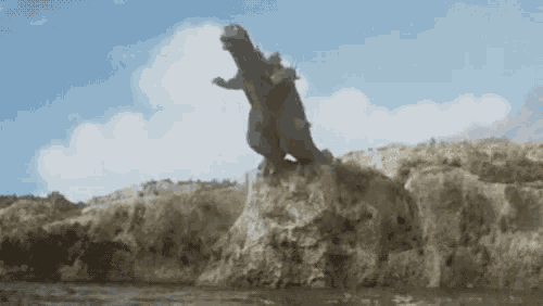 a large monster is standing on top of a large rock in the water .