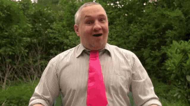 a man wearing a striped shirt and a pink tie is making a funny face .