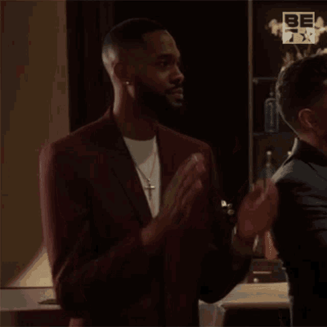 a man in a suit is applauding while standing next to another man in a suit .