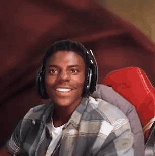 a young man wearing headphones and a plaid shirt is sitting in a chair .