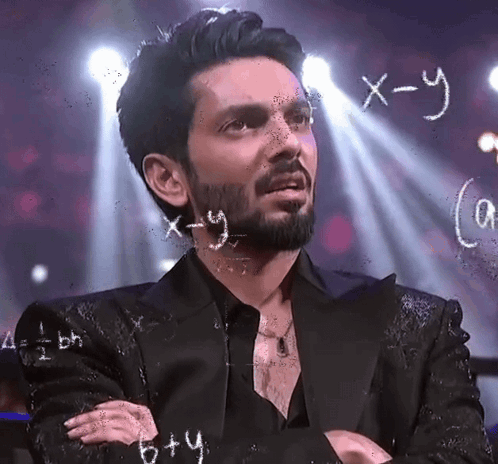 A man stands in front of chalkboard equations with a confused look.