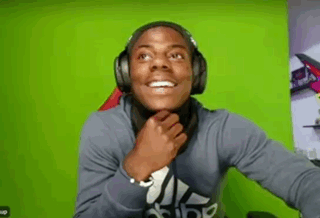 A headset-wearing streamer smiles in astonishment against a bright green background.