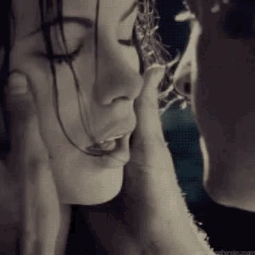 A couple lean in cheek-to-cheek for a tender kiss.