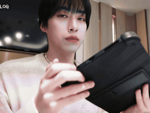a man is holding a tablet with the word log on the bottom right
