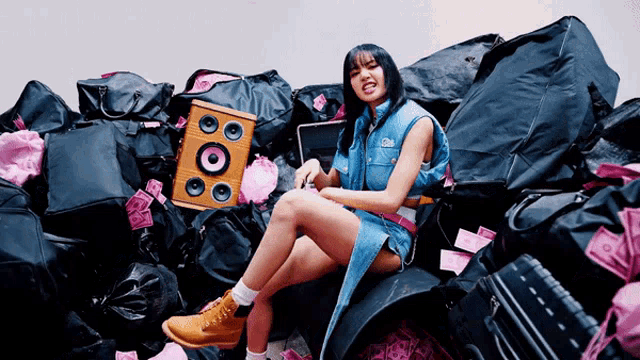 a woman is sitting in a pile of luggage with a speaker and headphones