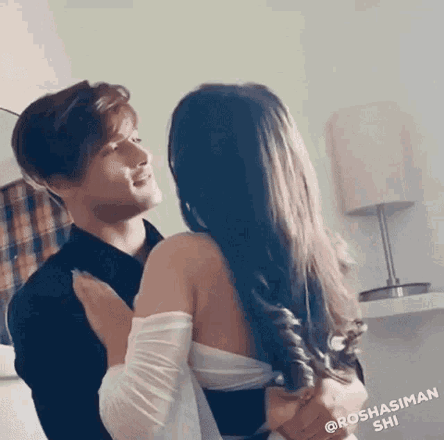 a man and a woman are hugging each other in a bedroom .