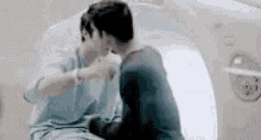 a couple of men are sitting next to each other in a bathtub and kissing .