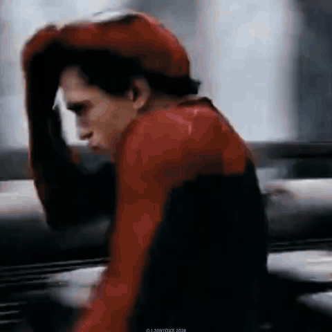a man wearing a red hat and a red jacket is holding his head .