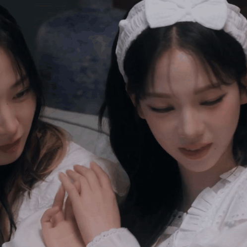 a woman wearing a white headband with a bow is holding another woman 's hand