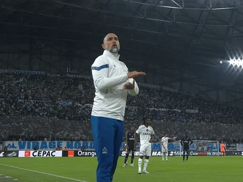 A soccer coach gestures in frustration on the sideline.